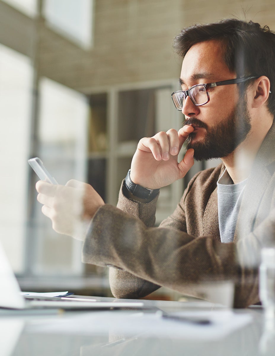Thoughtful man with computer and smartphone